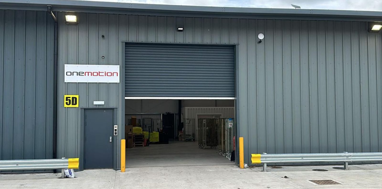 One Motion warehouse unit with its loading shutter open and roll cages inside